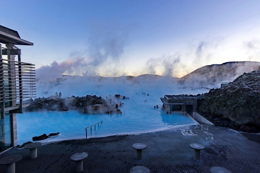 Geothermal hot spring surrounded by volcanic rocks and steam